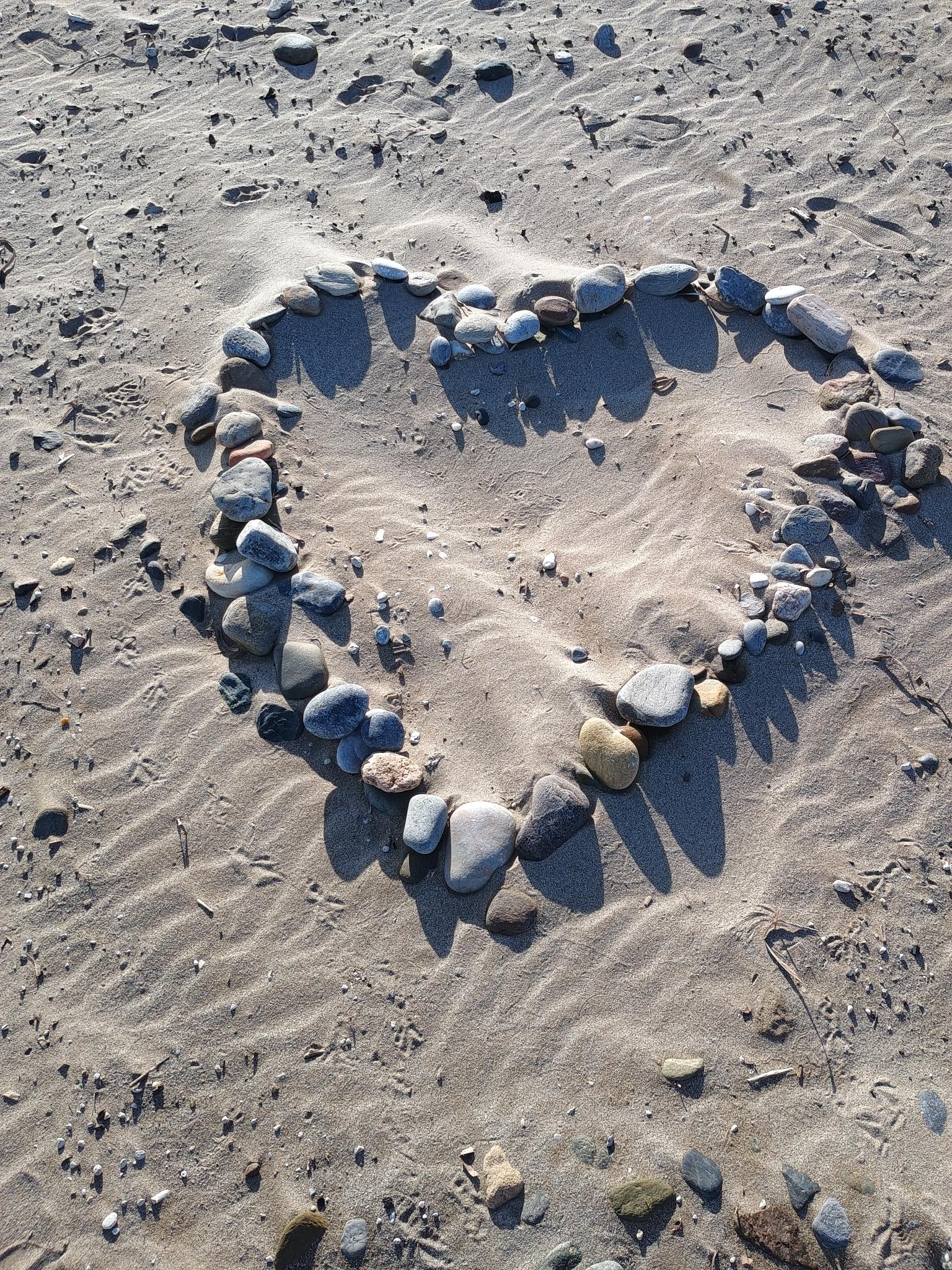 Heart shape made of stones in the sand on a Crete beach – symbol of connection